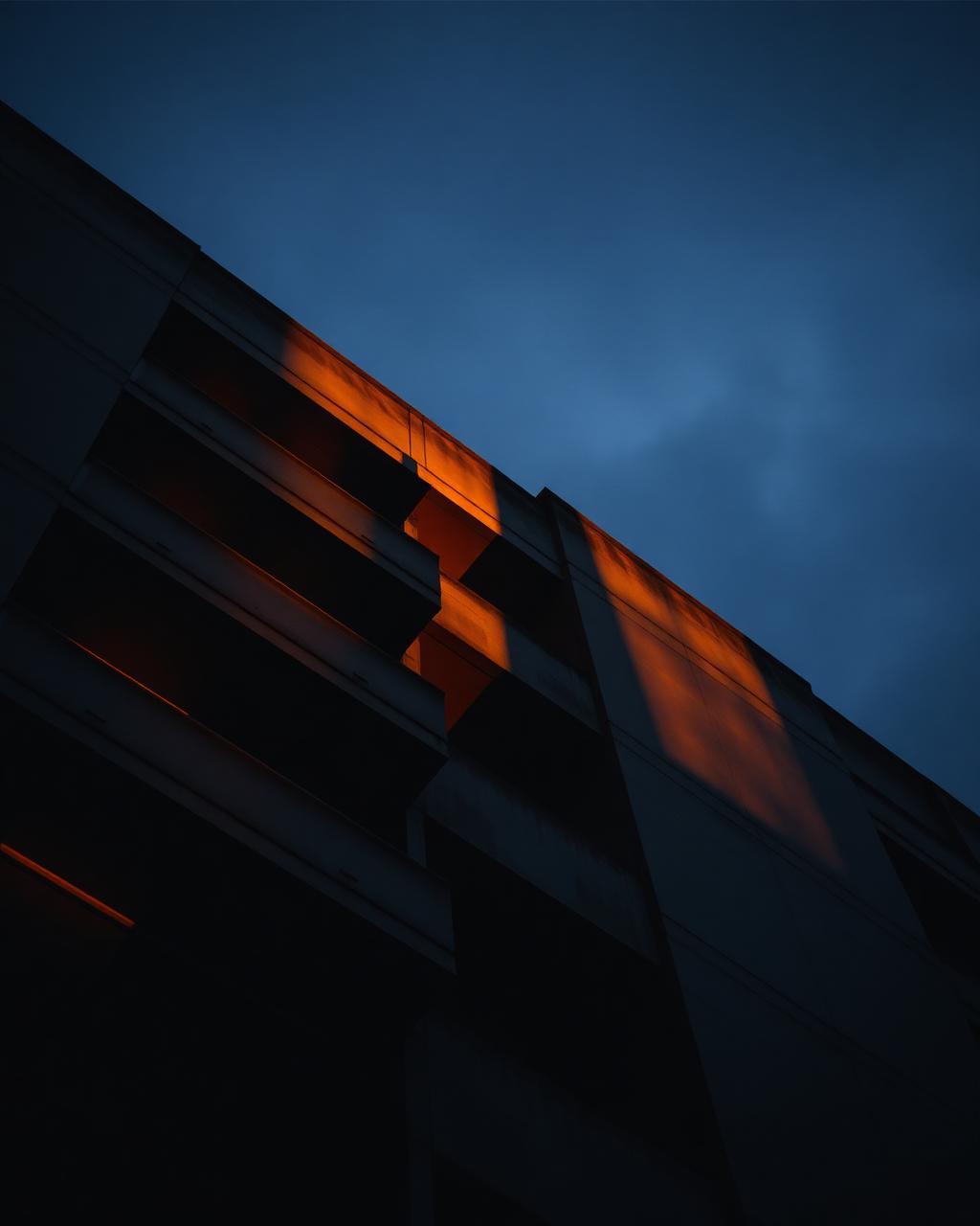 Brutalist concrete facade rendered in golden-hour light against an indigo twilight sky
